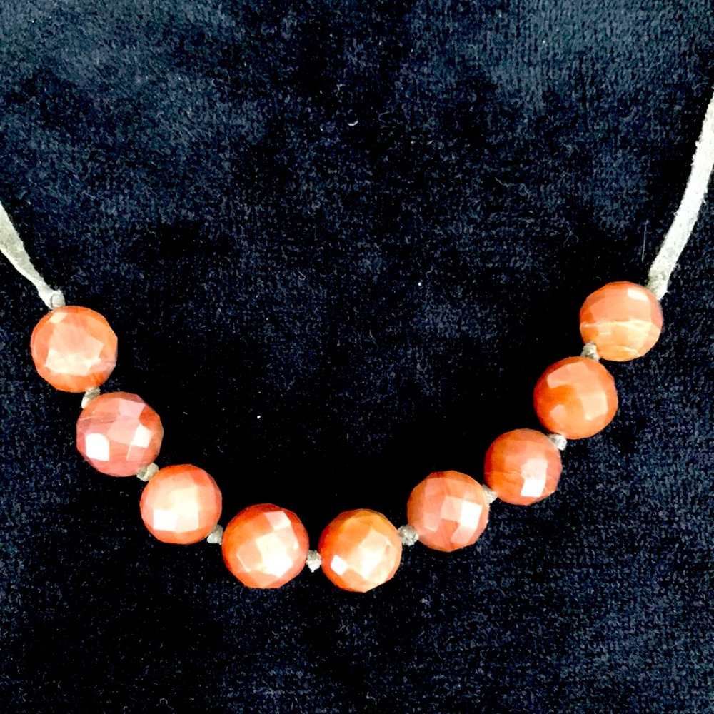 Reddish coral coloured beaded necklace on leather chain